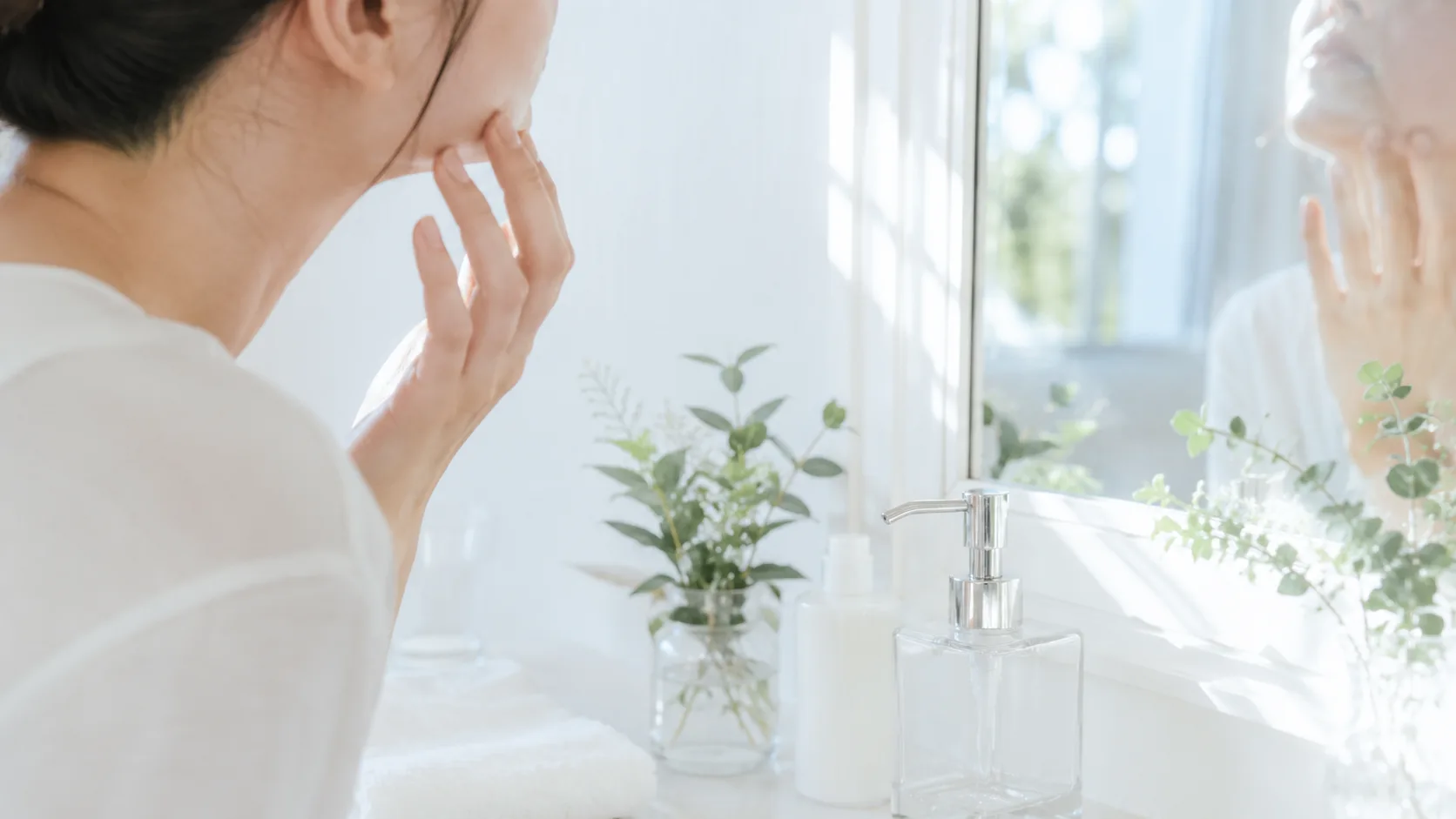 洗面台の鏡前で肌や髪の調子を確かめる手元